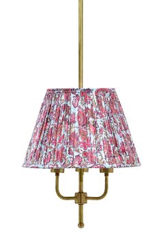 a pink and white lamp shade on an antique brass table lamp with floral print fabric