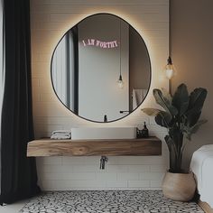 a bathroom with a round mirror above the sink and a potted plant next to it