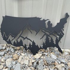 a metal sign with mountains and trees on it