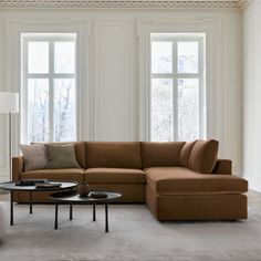 a living room with two couches and a coffee table in front of three windows