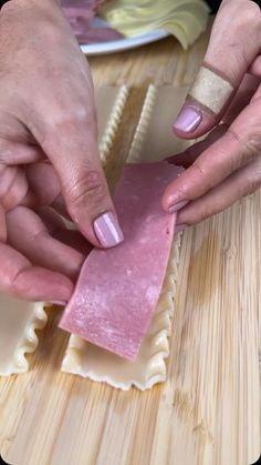 two people are making ravioli on a wooden table with one woman's hands