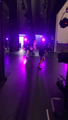 some people are skateboarding in a dark room with purple lights on the walls and floor