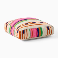 a multicolored striped pillow sitting on top of a white floor