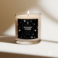 a lit candle with the words spooky cider written on it in black and white