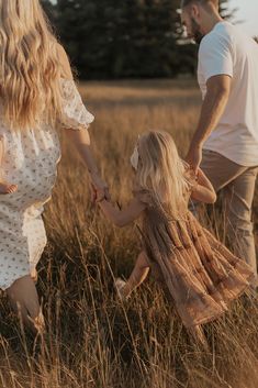 a family holding hands and walking through tall grass