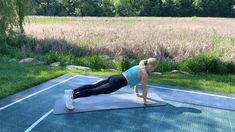 a woman is doing yoga on a mat in the middle of a field with grass and trees