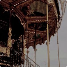 an old fashioned merry go round with lights on it's sides and railings