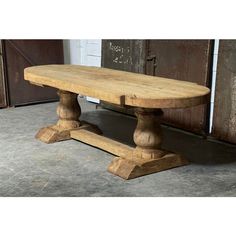 a wooden bench sitting on top of a cement floor next to an old barn door