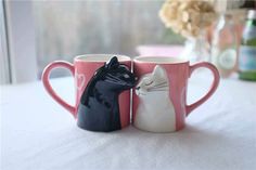 two coffee mugs with cats on them sitting next to each other