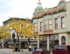 two cars are parked on the street in front of an old building with a green dome