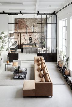 a living room filled with furniture next to a brick wall covered in mirrors and windows