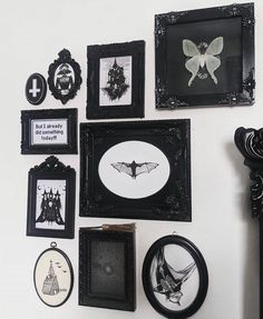 there are many framed pictures on the wall with black and white artwork hanging above them