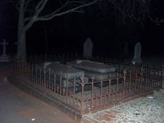 an old cemetery at night with tombstones in the foreground and trees on the other side