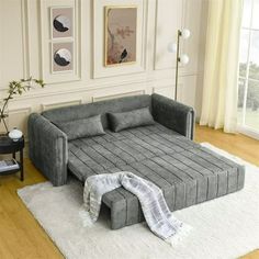 a living room with a gray couch and white rug on the floor, next to a window