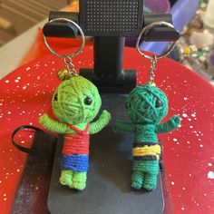 two small crocheted keychains sitting on top of a red table next to each other