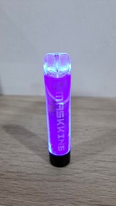 a purple light up tube sitting on top of a wooden table next to a white wall