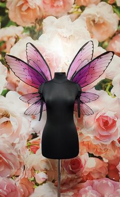 a mannequin with a purple butterfly wings on it's head in front of pink roses