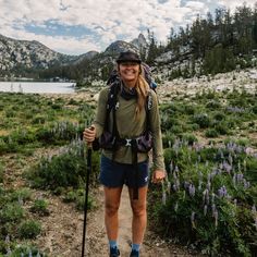 a woman hiking in the mountains with a backpack and trekking poles on her back