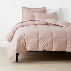 a bed with pink comforter and pillows on it