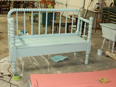 a white bench sitting on top of a floor next to other furniture and decor items