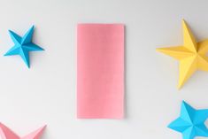 three paper stars next to each other on a white surface with pink and blue papers