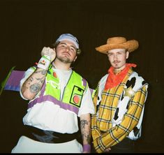 two men dressed in costumes standing next to each other with one holding a beer bottle