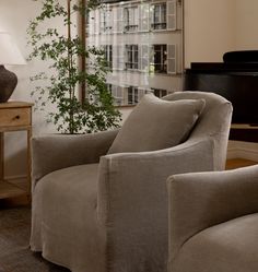 a living room filled with furniture next to a tall window and a piano in the background