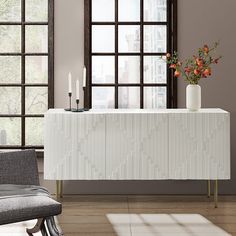 a white table with flowers and candles on it next to a chair in front of a window