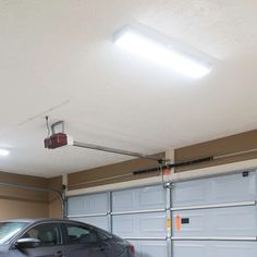 a car is parked in front of a garage door with overhead lights above it and on the ground