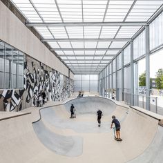 two skateboarders riding down the side of a ramp in a large indoor area