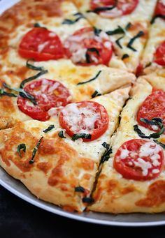 a close up of a pizza on a plate with tomatoes and basil toppings,