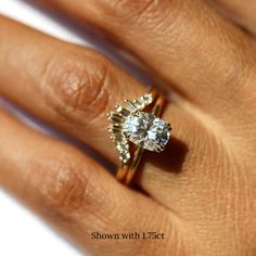 a woman's hand with a diamond ring on top of her finger and an engagement band