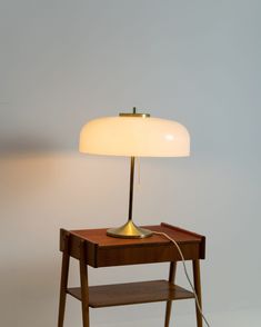 a table with a lamp on it and a shelf underneath the lamp that is plugged in