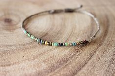 a close up of a beaded bracelet on a wooden table with wood grain background