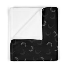 a black and white blanket with bats on it, sitting next to a folded sheet