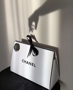 a person's shadow is cast on the back of a chanel box with scissors