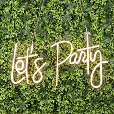 two neon signs that say lots party on top of some green plants in front of a wall