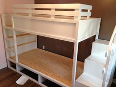 a white bunk bed sitting on top of a wooden floor next to a stair case