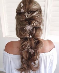 a woman with long hair in a half - up braid and flowers on her head