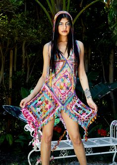 a woman in a colorful dress standing next to a bench