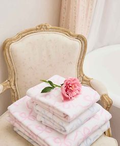 a stack of towels sitting on top of a chair next to a pink flower