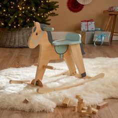 a wooden rocking horse sitting on top of a white rug next to a christmas tree