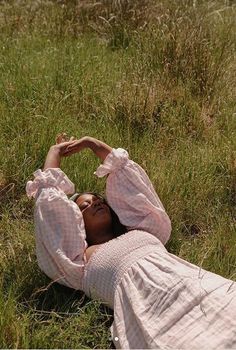 a woman laying on the ground in tall grass