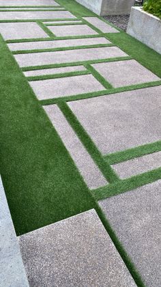 an artificial lawn with grass in the middle and concrete blocks on each side that are lined up