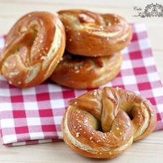 four bagels sitting on top of a red and white checkered napkin next to each other