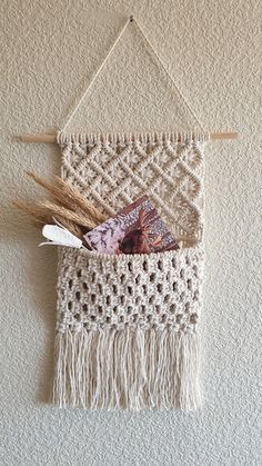 the wall hanging is made with yarn and feathers