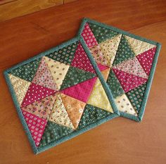 two quilted coasters sitting on top of a wooden table