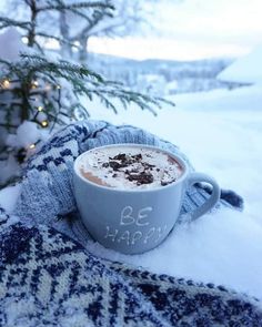 a cup of hot chocolate sitting on top of snow covered ground