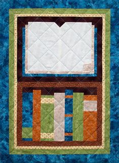 a close up of a quilted wall hanging on the side of a blue wall