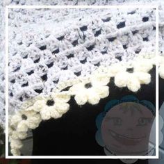 a crocheted blanket with white flowers on it and a smiling child's face